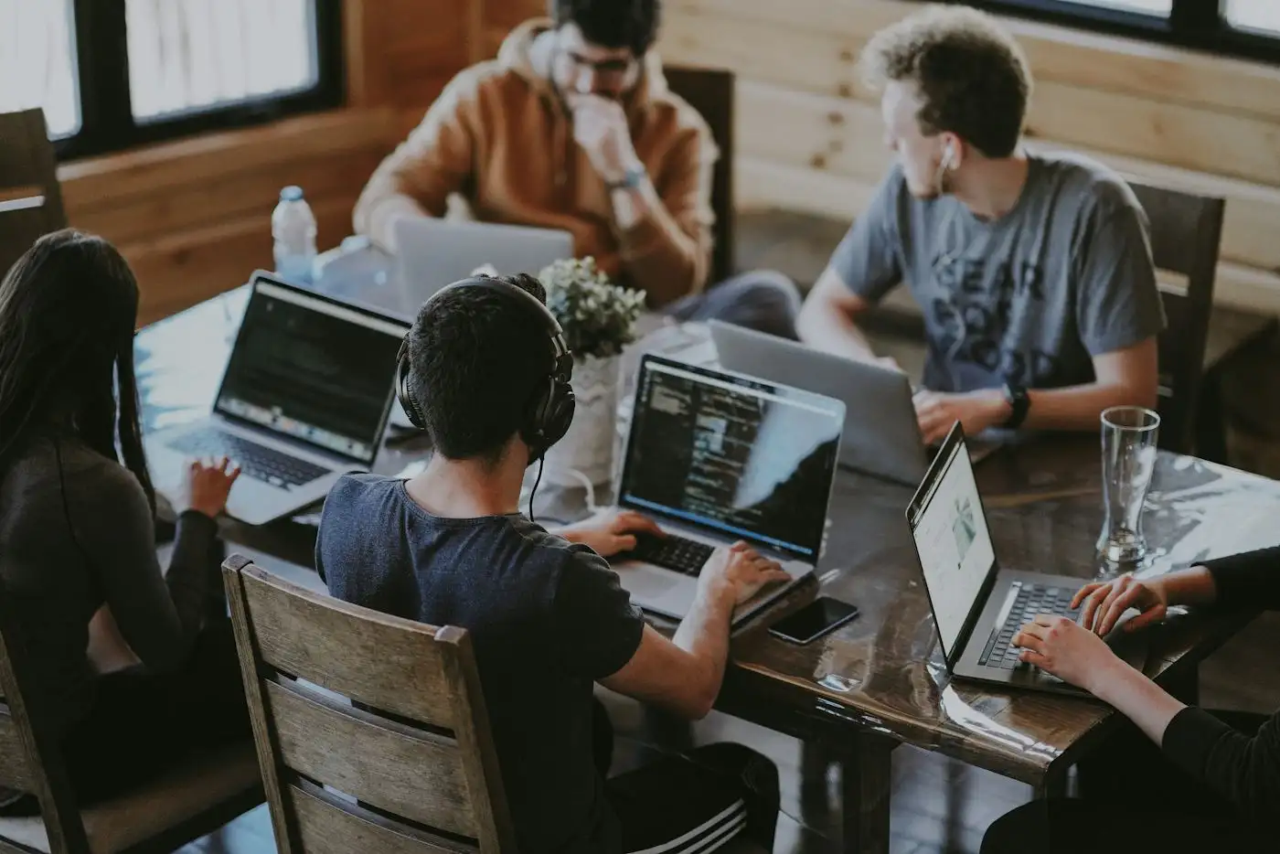 A small team working on laptops around a wooden table